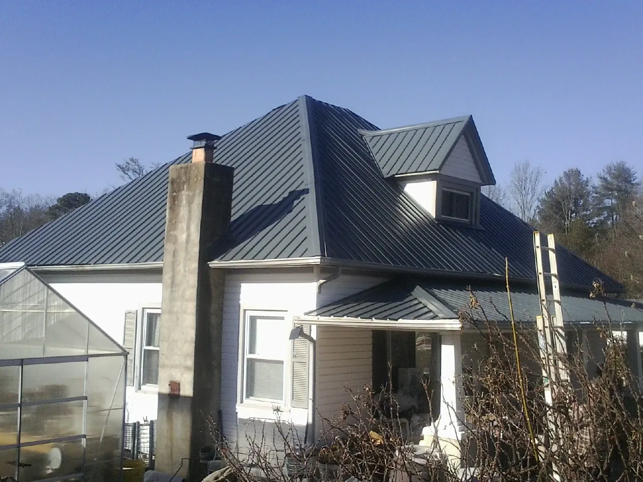 Dark blue standing seam metal roof on a white farmhouse with dormer — Slate & Tile Roof Repair by Roofing Brothers in Rossville