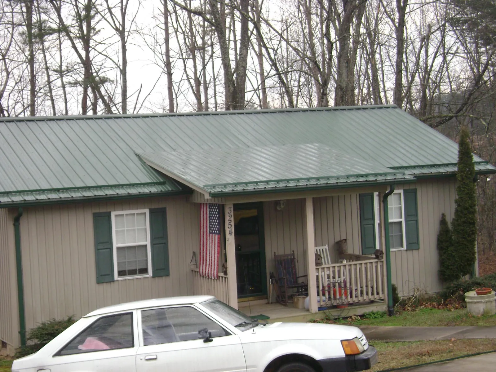 Green metal roof and front porch on a tan sided cottage in Rossville