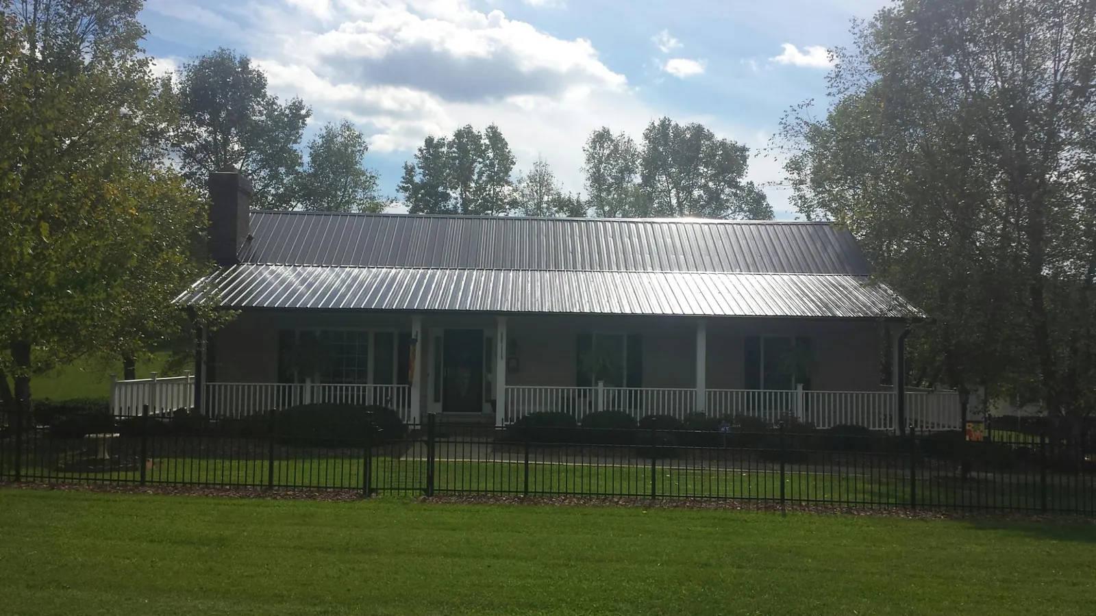 Gray metal roof on a brick ranch with a full width front porch — Gutter Guard Installation work by our crew in Rossville